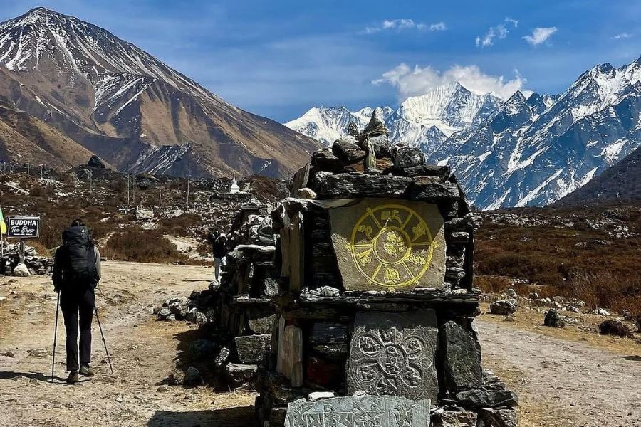 Stone Buddhist stupa with prayer wheels against backdrop of Langtang mountain range